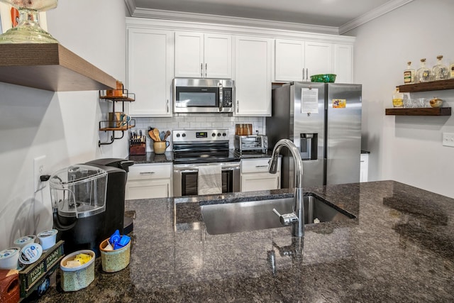 kitchen with stainless steel appliances, dark stone countertops, ornamental molding, white cabinets, and sink