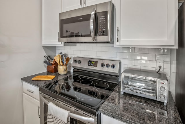 kitchen featuring decorative backsplash, white cabinetry, appliances with stainless steel finishes, and dark stone countertops