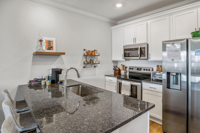 kitchen with white cabinets, appliances with stainless steel finishes, sink, and dark stone countertops