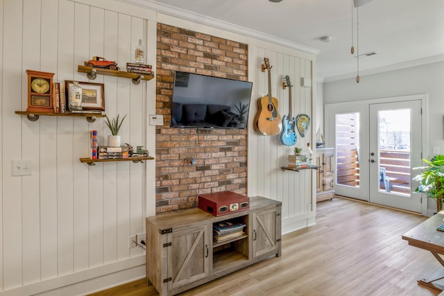 interior space with light wood-type flooring, ornamental molding, and french doors