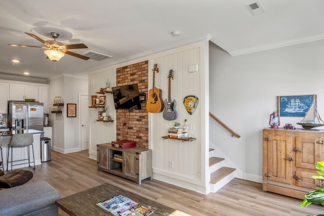 living room featuring ceiling fan, ornamental molding, and light hardwood / wood-style flooring