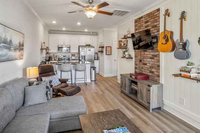 living room with ceiling fan, light wood-type flooring, and ornamental molding