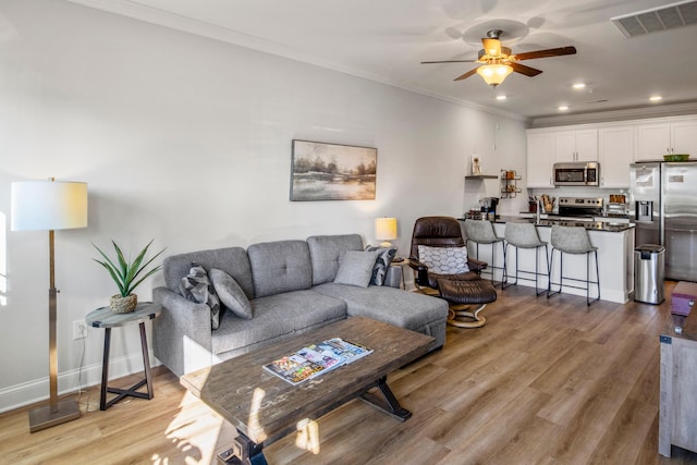 living room featuring light hardwood / wood-style floors, sink, ornamental molding, and ceiling fan