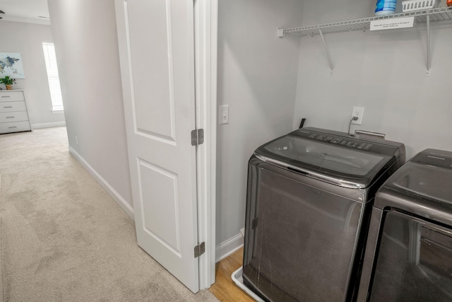 laundry area featuring washer and clothes dryer, ornamental molding, and light carpet