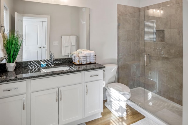 bathroom with hardwood / wood-style floors, walk in shower, vanity, and toilet