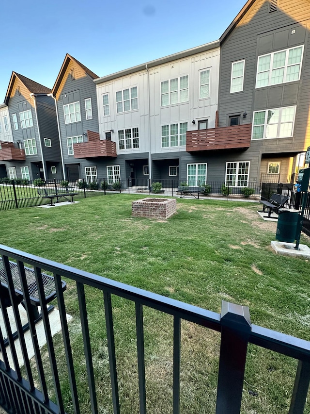 back of property with an outdoor fire pit and a yard