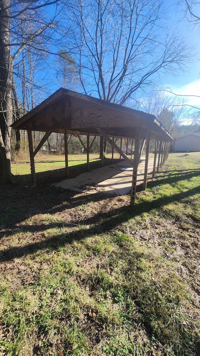 view of vehicle parking featuring a lawn and a carport