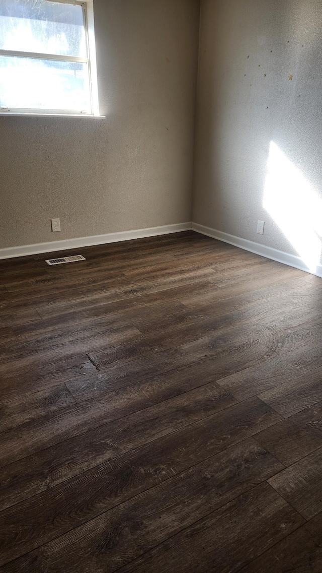 unfurnished room with dark wood-type flooring