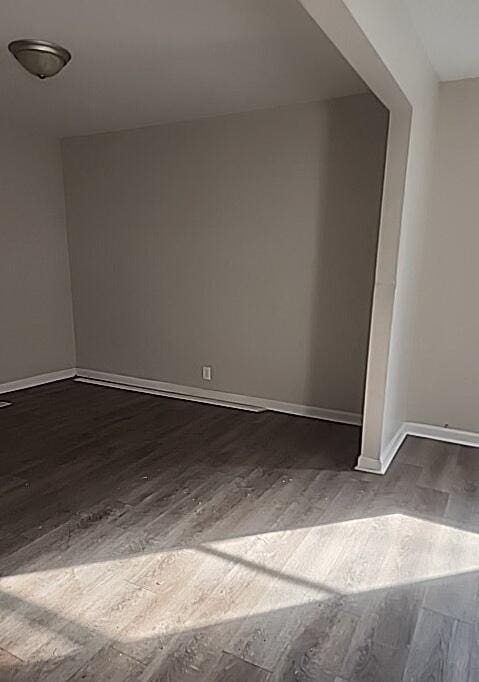 unfurnished room with dark wood-type flooring