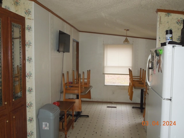 kitchen with crown molding, decorative light fixtures, white refrigerator, and a textured ceiling