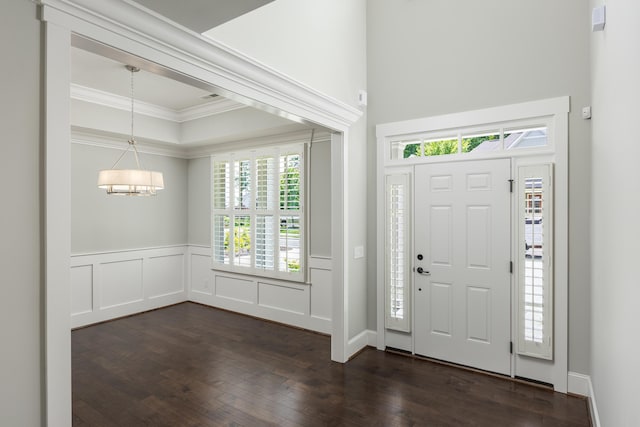 entryway featuring dark hardwood / wood-style flooring, crown molding, and a chandelier