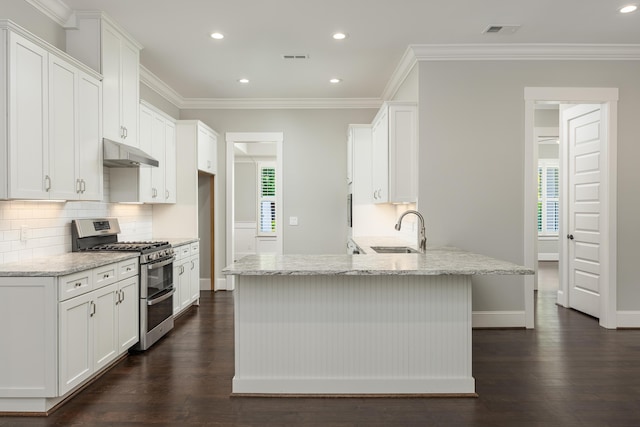 kitchen with light stone counters, sink, range with two ovens, and kitchen peninsula