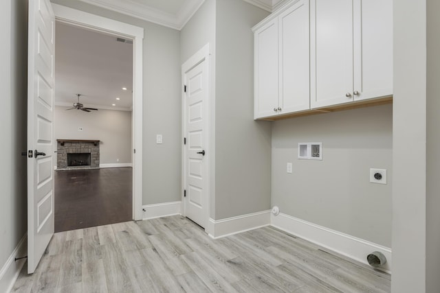 washroom featuring crown molding, hookup for a washing machine, a stone fireplace, hookup for an electric dryer, and cabinets