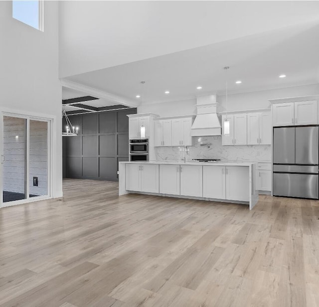 kitchen with decorative light fixtures, white cabinetry, stainless steel appliances, and custom exhaust hood