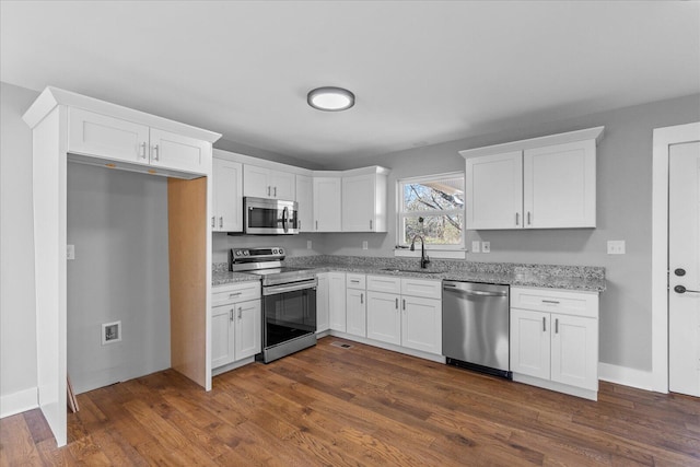 kitchen featuring white cabinets, appliances with stainless steel finishes, dark hardwood / wood-style flooring, sink, and light stone counters