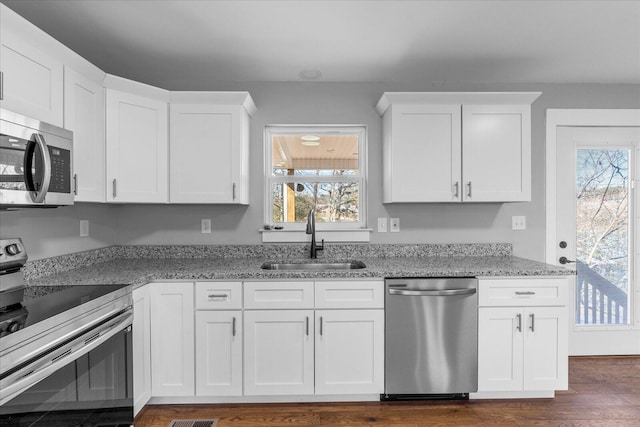 kitchen with light stone countertops, sink, white cabinets, and stainless steel appliances