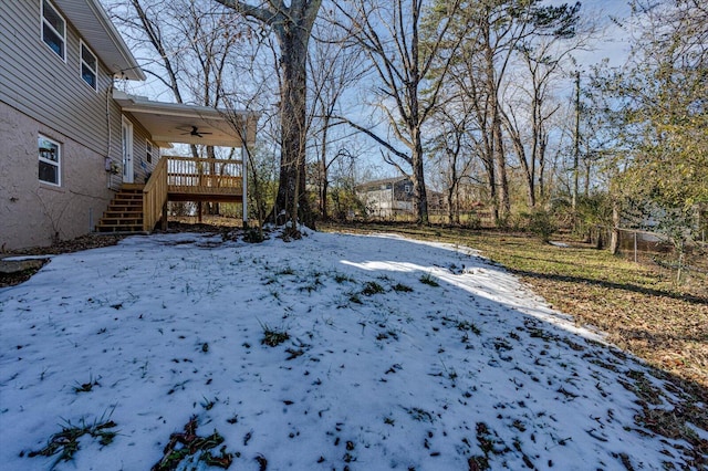 yard covered in snow with ceiling fan and a deck