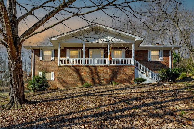 view of front of house with brick siding, stairway, and a porch