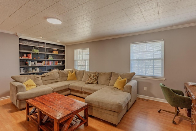 living area with crown molding, light wood-style flooring, built in shelves, and baseboards