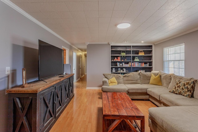 living room featuring built in features, baseboards, light wood-style flooring, and crown molding