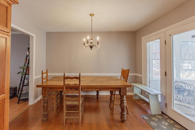 dining room featuring an inviting chandelier, wood finished floors, and baseboards