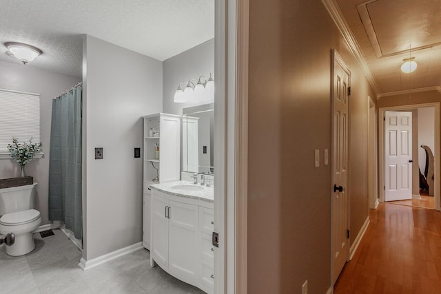 full bathroom with vanity, baseboards, a textured ceiling, crown molding, and toilet