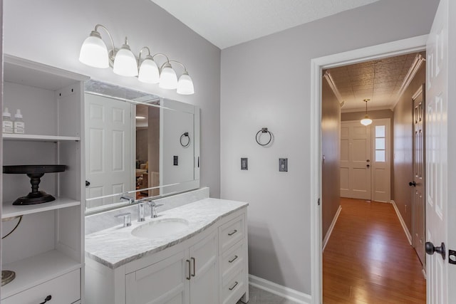 bathroom featuring ornamental molding, vanity, baseboards, and wood finished floors