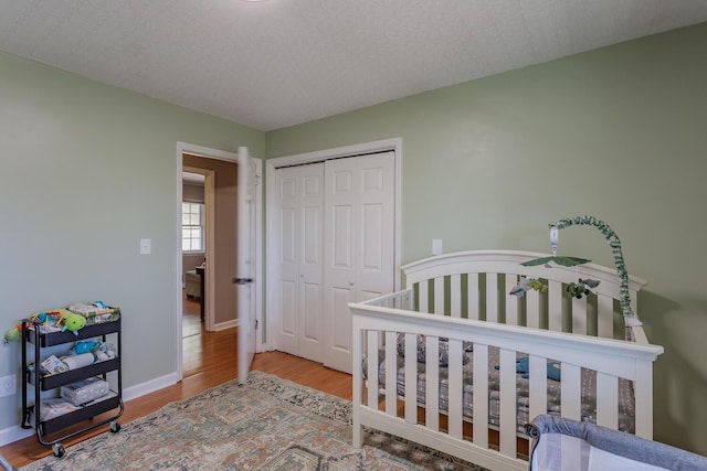 bedroom featuring a closet, a textured ceiling, baseboards, and wood finished floors