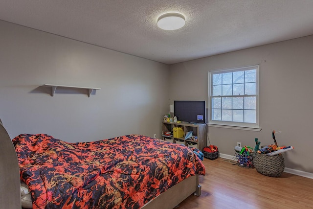 bedroom featuring wood finished floors, baseboards, and a textured ceiling