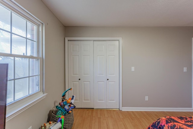 unfurnished bedroom with a closet, baseboards, and light wood-style floors