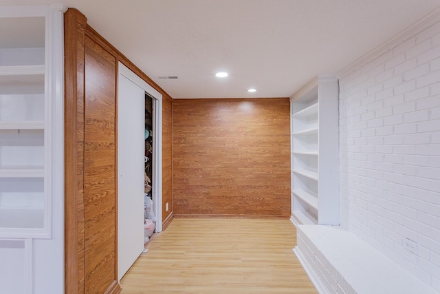 hall with wooden walls, built in shelves, recessed lighting, and light wood-type flooring