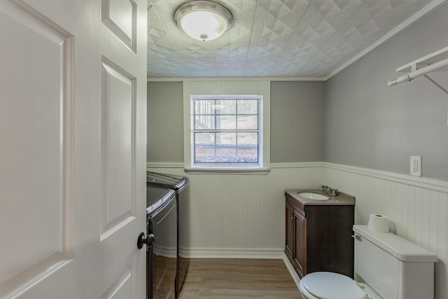 bathroom featuring vanity, toilet, wainscoting, and washing machine and clothes dryer