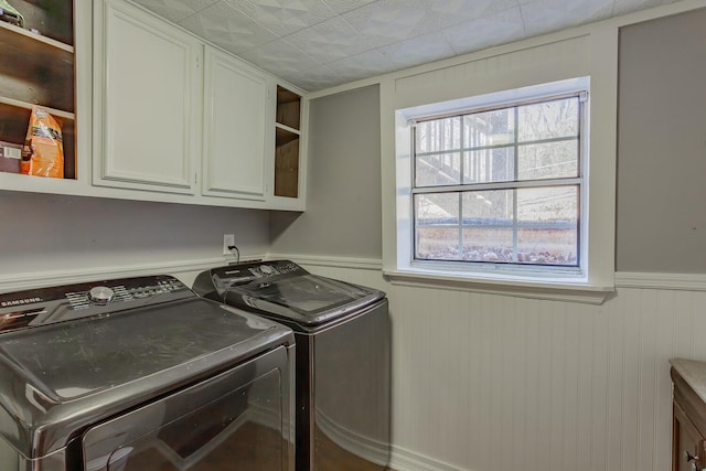 laundry area with washer and clothes dryer, cabinet space, and wainscoting