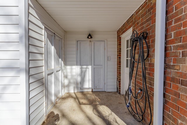 doorway to property featuring brick siding and covered porch