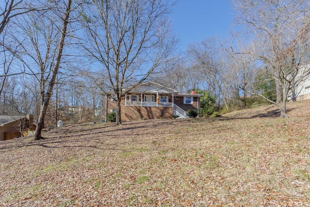 view of front of property featuring brick siding, a porch, and stairs