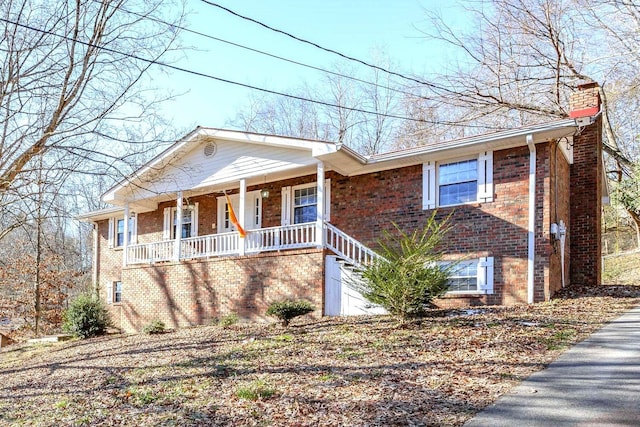 view of front of home with brick siding, covered porch, and a chimney