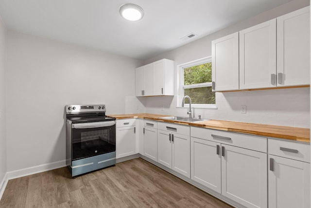 kitchen featuring electric stove, light hardwood / wood-style floors, butcher block countertops, sink, and white cabinetry