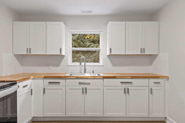 kitchen featuring wood counters, white cabinetry, stainless steel electric stove, and sink