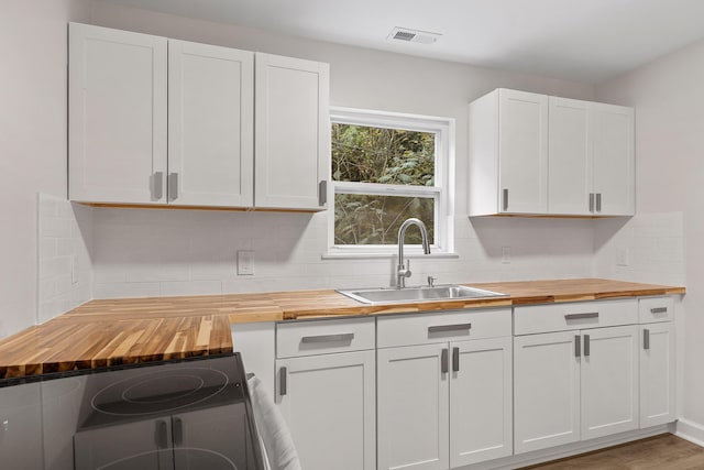 kitchen with white cabinetry, hardwood / wood-style floors, wooden counters, electric range, and sink