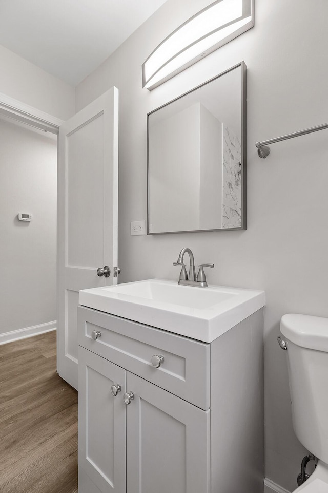 bathroom with toilet, vanity, and hardwood / wood-style flooring