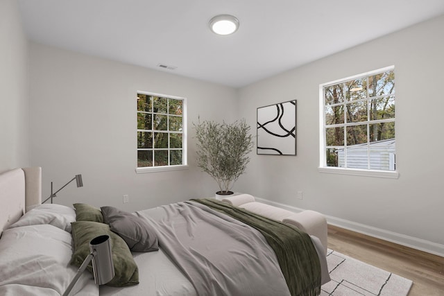 bedroom with multiple windows and light hardwood / wood-style floors