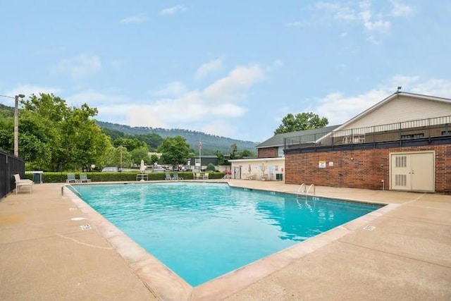 view of swimming pool with a patio area and a mountain view