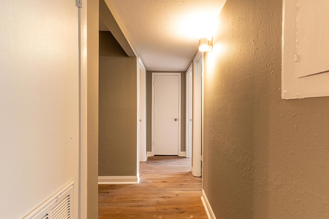 hall with light wood-type flooring and electric panel