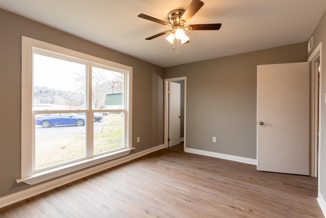 unfurnished room with ceiling fan, light wood-type flooring, and plenty of natural light