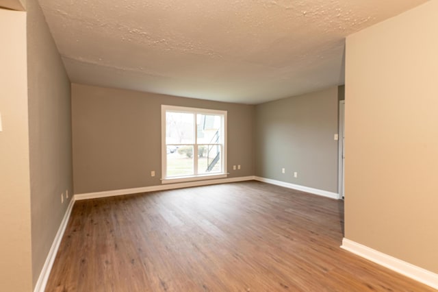 empty room featuring wood-type flooring and a textured ceiling