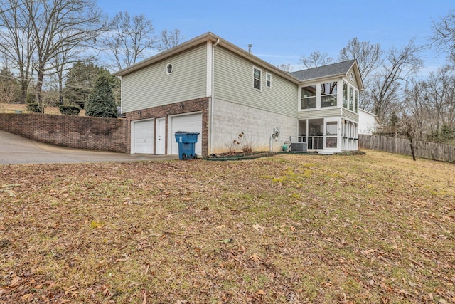 back of house featuring a garage, a sunroom, a yard, and central AC