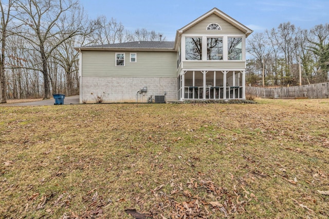 rear view of property featuring central AC unit, a sunroom, and a lawn