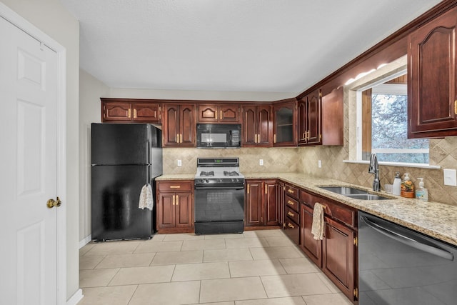 kitchen featuring tasteful backsplash, sink, light tile patterned floors, and black appliances