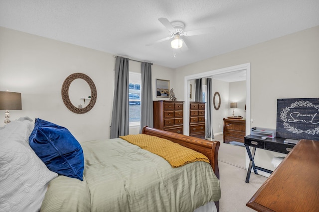 bedroom with a textured ceiling, light colored carpet, and ceiling fan