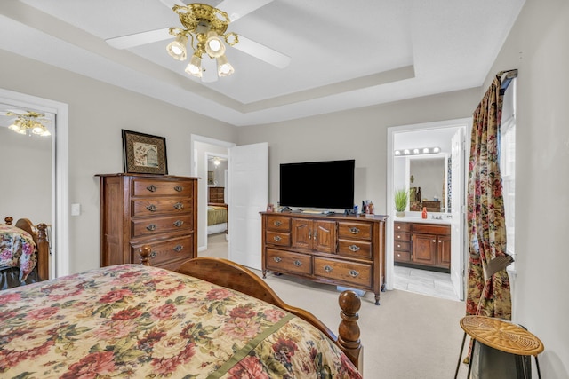 bedroom with ceiling fan, ensuite bathroom, a raised ceiling, and light carpet